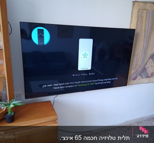 טלוויזיה תלויה על הקיר עם כבלים חשמליים גלויים